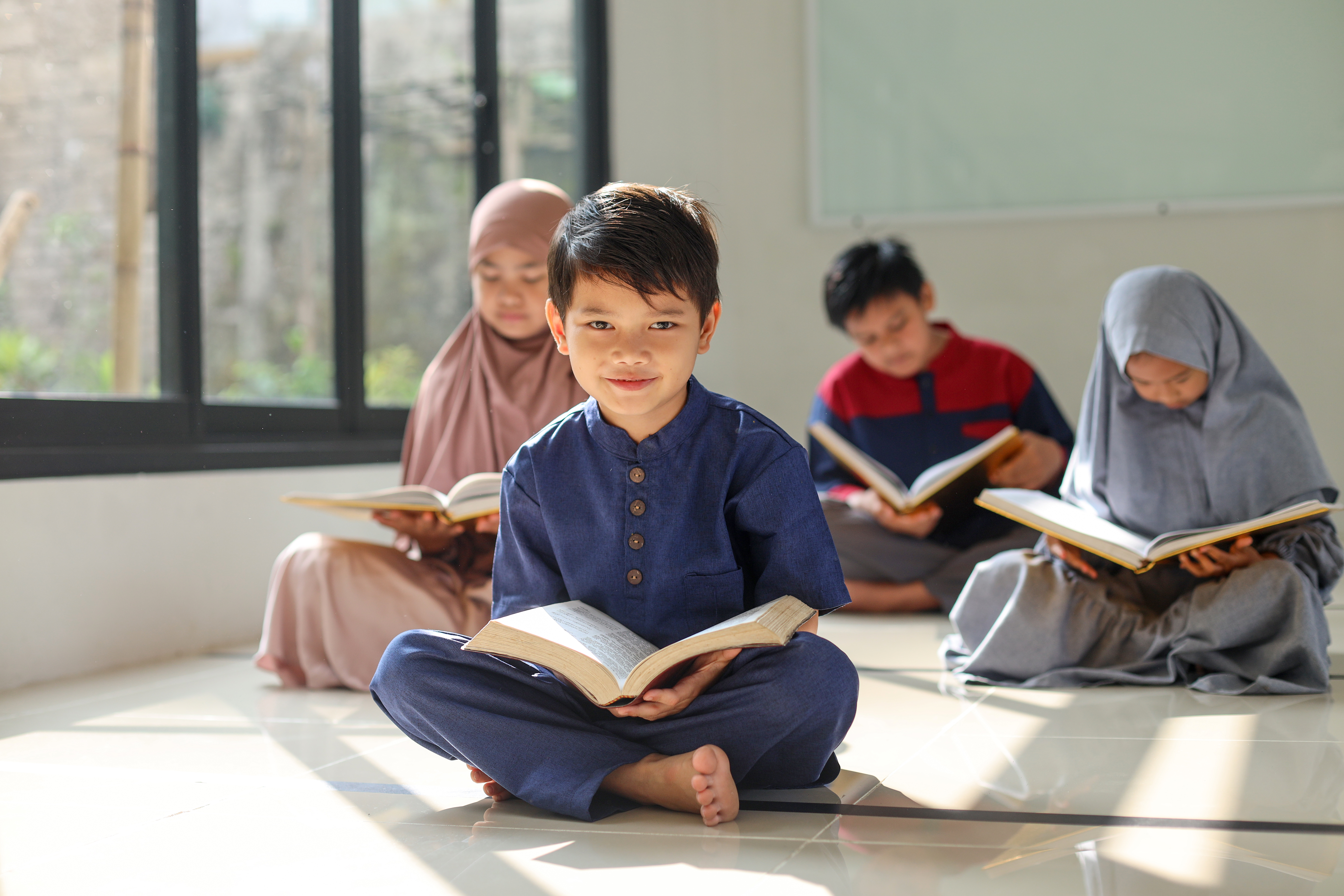 A cute little boy smiling at camera after reading the Koran with friends